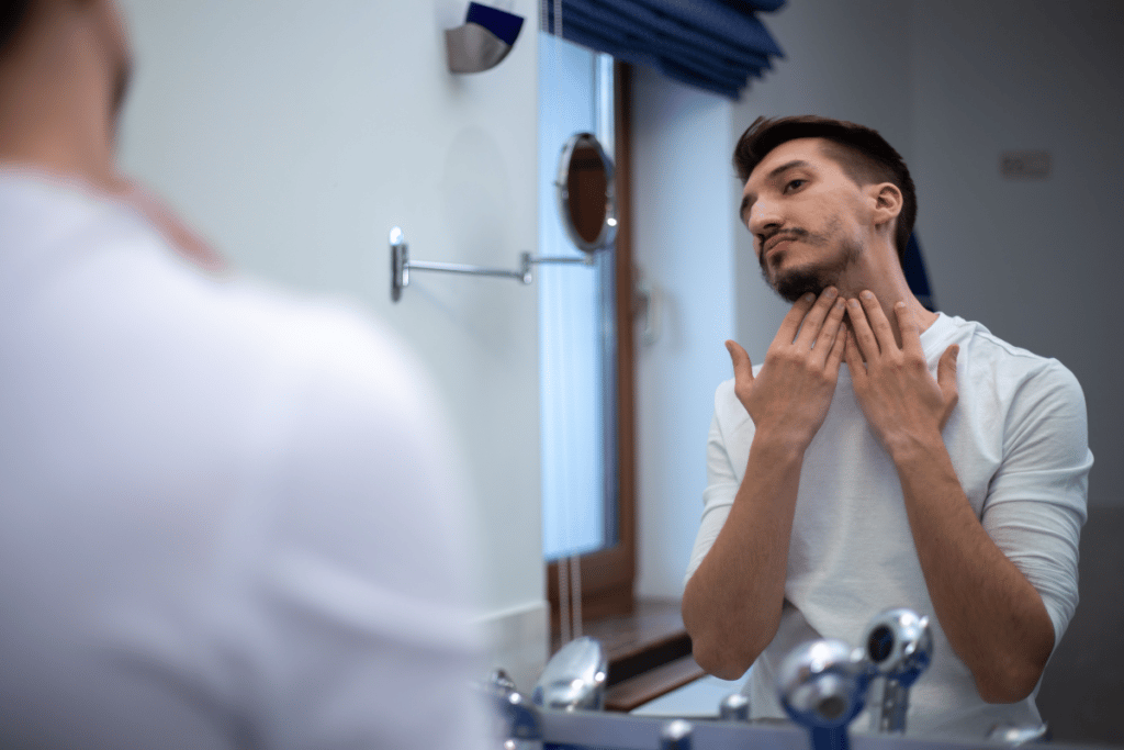 man looking a thin, patchy beard in the mirror