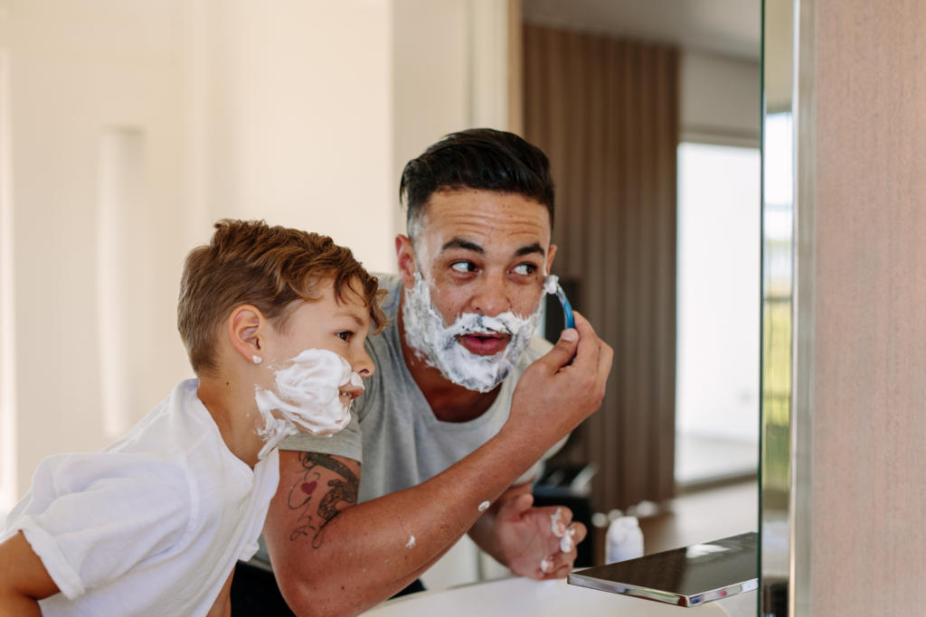 Dad and son shaving in the mirror - Does shaving cream or soap help make a shave better?